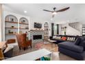 Open living room with fireplace, modern ceiling fan, hardwood floors, built in shelves, and comfortable furnishings at 8740 W San Miguel Ave, Glendale, AZ 85305