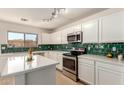 Well lit kitchen with white cabinets, stainless steel appliances, and green subway tile at 9643 N 81St Dr, Peoria, AZ 85345