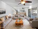 Bright living room with a gray sofa set, plush rug, and a view into the modern kitchen at 11020 N 45Th Ave, Glendale, AZ 85304