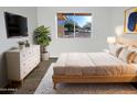 Bright main bedroom with a queen bed, white dresser, rug, and a view to the street at 11020 N 45Th Ave, Glendale, AZ 85304