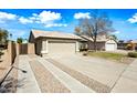Single-story home featuring an extended driveway with decorative gravel and a beige garage door at 14398 W Marcus Dr, Surprise, AZ 85374