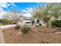 Inviting home featuring manicured landscaping with rock accents and covered front patio at 16210 W Desert Winds Dr, Surprise, AZ 85374