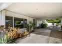 A covered patio featuring lush plants and shade, with a glimpse of the outdoors through large windows at 18256 N 75Th Ave, Glendale, AZ 85308