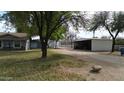 A backyard showcases mature shade trees and several outbuildings, including a barn, adding character and utility to the property at 4311 W Siesta Way, Laveen, AZ 85339