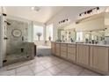 A bathroom featuring both a shower and a bathtub surrounded by beige tiling, windows, and a long vanity at 4531 W Flint St, Chandler, AZ 85226