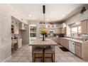 Well-lit kitchen featuring an island with seating, tiled countertops, and modern appliances at 4531 W Flint St, Chandler, AZ 85226