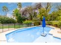 Inviting backyard pool with a blue umbrella and fence, surrounded by lush greenery and palm trees at 4558 E Vista Dr, Phoenix, AZ 85032