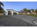 Modern home showcasing a spacious driveway, desert landscaping, and a multi-car garage at 8040 E Carol Way, Scottsdale, AZ 85260