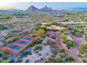 Expansive aerial view of desert estate featuring multiple buildings and a red-and-green tennis court at 9716 E Mariposa Grande Dr, Scottsdale, AZ 85255