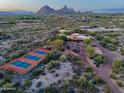 Aerial view features the property with mountain views, a tennis court and desert landscaping at 9716 E Mariposa Grande Dr, Scottsdale, AZ 85255