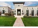 Elegant gray home featuring manicured landscaping, a brick pathway, and a grand entryway with decorative stone accents at 10244 E Hualapai Dr, Scottsdale, AZ 85255