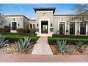 Elegant gray home featuring manicured landscaping, a brick pathway, and a grand entryway with decorative stone accents at 10244 E Hualapai Dr, Scottsdale, AZ 85255