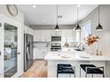 Bright, white kitchen with stainless steel appliances and a large island featuring stylish pendant lighting at 10823 W Polk St, Avondale, AZ 85323