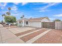 Front exterior of a bright white home with desert landscaping, covered entryway, and spacious driveway at 11430 N 57Th Dr, Glendale, AZ 85304