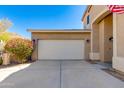 A view of the attached two car garage with a concrete driveway and lush landscaped area nearby at 2525 W Sat Nam Way, Phoenix, AZ 85086