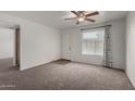 Bright living room showcasing plush carpeting, a ceiling fan, and a front-facing window at 461 W Holmes Ave # 277, Mesa, AZ 85210