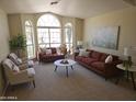 Bright living room with neutral carpet, modern sofas, decorative pillows, and large arched windows at 5381 W Del Rio St, Chandler, AZ 85226