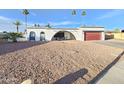 Single-story home featuring a desert landscaped front yard, red garage door and architectural charm at 8227 N 47Th Dr, Glendale, AZ 85302