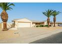 Attractive single-story home with two-car garage, desert landscaping, and mature palm trees at 9634 W Glen Oaks N Cir, Sun City, AZ 85351