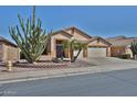 Inviting single-story home featuring a three-car garage and desert landscaping with a mature cactus and palm trees at 12814 W Windrose Dr, El Mirage, AZ 85335