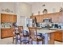 Eat-in kitchen with stainless steel appliances, wooden cabinets, and a center island with bar stool seating at 12814 W Windrose Dr, El Mirage, AZ 85335