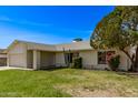 Inviting home exterior with a lush green lawn, mature trees, and desert landscaping at 14426 N 52Nd Ave, Glendale, AZ 85306