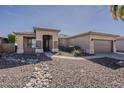 A tan single-story home with desert landscaping, stone accents, and a two-car garage at 14837 W Crocus Dr, Surprise, AZ 85379