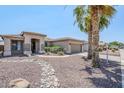 Charming home featuring desert landscaping, natural rock features, and mature palm trees at 14837 W Crocus Dr, Surprise, AZ 85379
