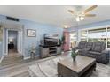 Cozy living room with light blue walls, a ceiling fan, comfortable seating, and wood-look floors at 15621 N Lakeforest Dr, Sun City, AZ 85351