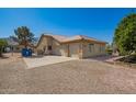 Tan single-story home with a three-car garage and a gravel driveway at 17203 E Starflower Ct, Queen Creek, AZ 85142