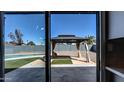 View from sliding glass doors to backyard featuring a gazebo, artificial turf, and a glimpse of the pool at 2110 W Pampa Ave, Mesa, AZ 85202