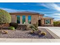 Tan single-Gathering home with rock landscaping and desert plants out front with a small tree on the left side at 25983 W Escuda Dr, Buckeye, AZ 85396