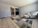 Cozy living room featuring neutral-toned tile flooring and a comfortable armchair with an ottoman at 1210 E Marny Rd, Tempe, AZ 85288