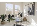 Bright home office with a modern glass desk, art, and ample natural light at 15580 S 181St Ln, Goodyear, AZ 85338