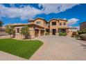 Impressive exterior of a well-maintained home with a spacious driveway and manicured lawn under a clear blue sky at 18436 E Celtic Manor Dr, Queen Creek, AZ 85142