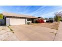 A single-story home featuring an attached garage and a large driveway at 323 N Hunt E Dr, Mesa, AZ 85203