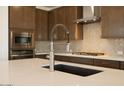 Close-up of kitchen island with quartz countertop, stainless steel faucet, tile backsplash, and cabinet hardware at 40250 N Alegre Dr, San Tan Valley, AZ 85140