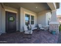 Cozy front porch with comfortable seating, brick flooring, and a decorative wreath on the front door at 5621 N 189Th Dr, Litchfield Park, AZ 85340