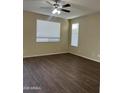 Cozy bedroom with a ceiling fan, wood-look flooring, and bright, natural light from windows at 6819 S 38Th Dr, Phoenix, AZ 85041