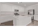 Bright kitchen features white cabinets, stainless steel appliances, quartz countertops, and wood-look tile flooring at 12378 W Marguerite Ave, Avondale, AZ 85323