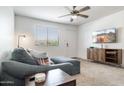 Living room with modern gray sofa, ceiling fan, and TV mounted on the wall at 5995 N 78Th St # 2079, Scottsdale, AZ 85250