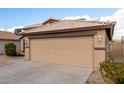 This charming home has a two-car garage, desert landscaping, and a tile roof at 1100 E Vernoa St, San Tan Valley, AZ 85140