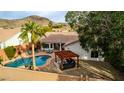 Aerial view of the backyard with a sparkling pool, covered patio, lush landscaping, and a seating area at 1356 E Desert Flower Ln, Phoenix, AZ 85048