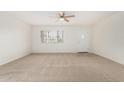 Bright living room featuring neutral carpet, a ceiling fan, and a window overlooking the front yard at 1817 W Claremont St, Phoenix, AZ 85015