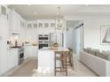 Open-concept kitchen with white cabinetry, island seating, stainless steel appliances, and seamless connection to the living area at 20318 W Turney Ave, Buckeye, AZ 85396