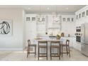 Bright white kitchen featuring a large island with barstool seating and pendant lighting and stainless steel appliances at 20318 W Turney Ave, Buckeye, AZ 85396