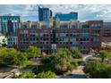 Beautiful brick building featuring many windows, lush green trees, and a view of surrounding buildings and blue skies at 21 E 6Th St # 412, Tempe, AZ 85281