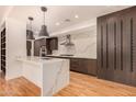 A modern kitchen with pendant lights, waterfall island, and dark wood cabinets at 2336 N 12Th St, Phoenix, AZ 85006