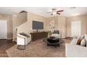 Neutral living room with a ceiling fan, plush carpet, cozy seating and stairs to the second floor at 35973 W Velazquez Dr, Maricopa, AZ 85138