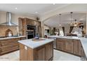 Bright kitchen with stainless steel appliances, an island with a white countertop and wood cabinets at 4068 N 155Th Ln, Goodyear, AZ 85395